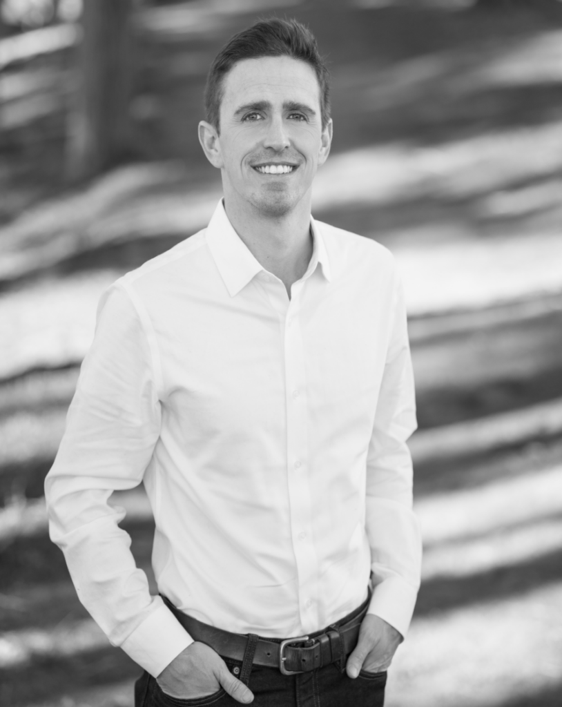 Man in a white shirt with trees.