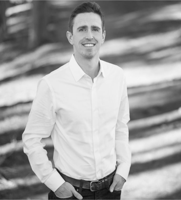 Man in a white shirt with trees.