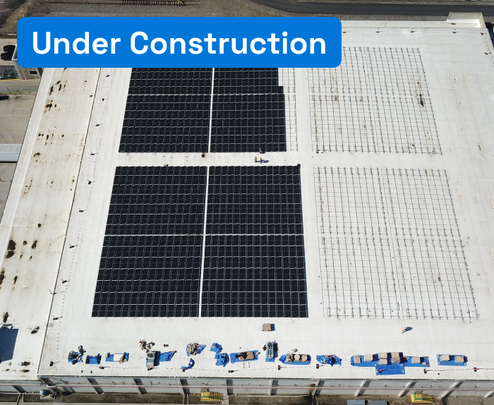 Aerial view of a solar plant being constructed on a warehouse roof, with 