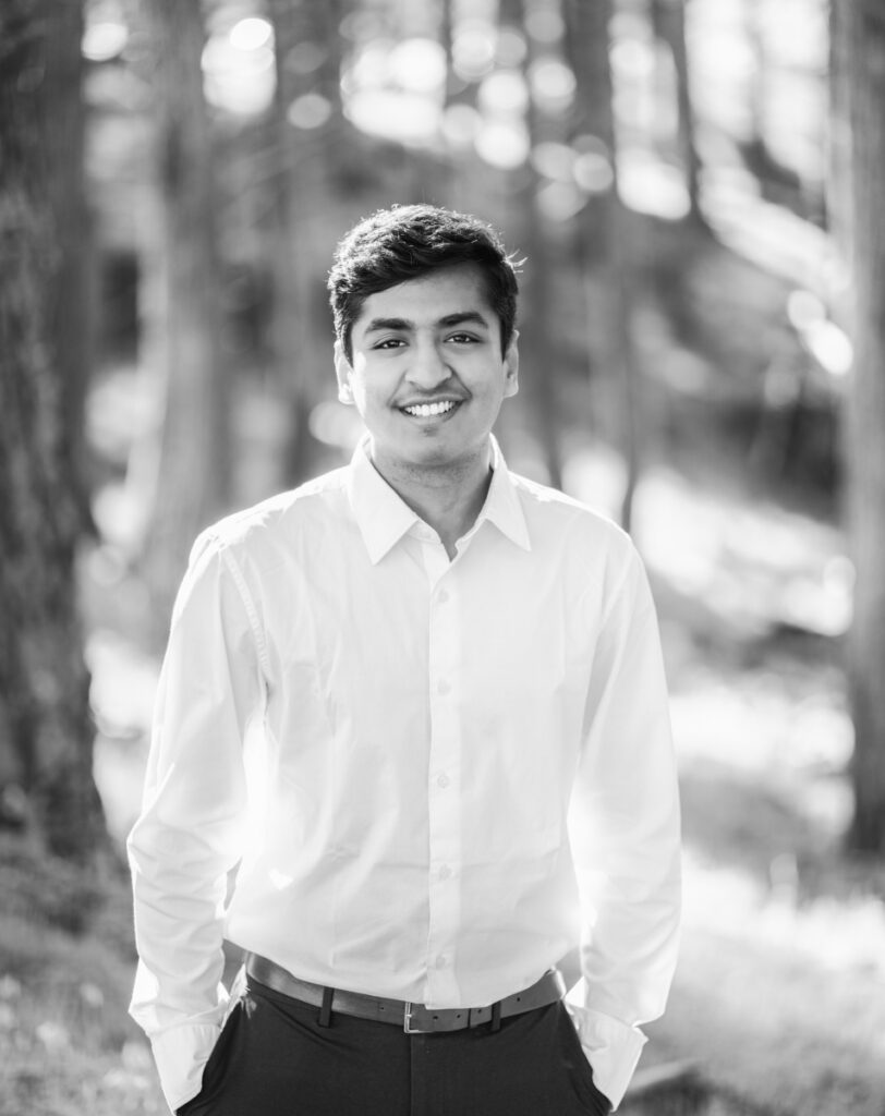 Black and white image of a young man with a forest as background.