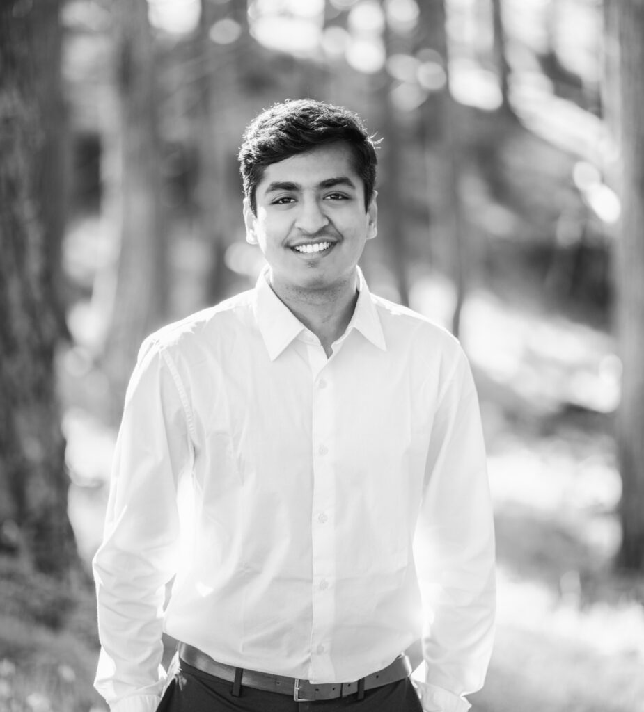 Black and white image of a young man with a forest as background.