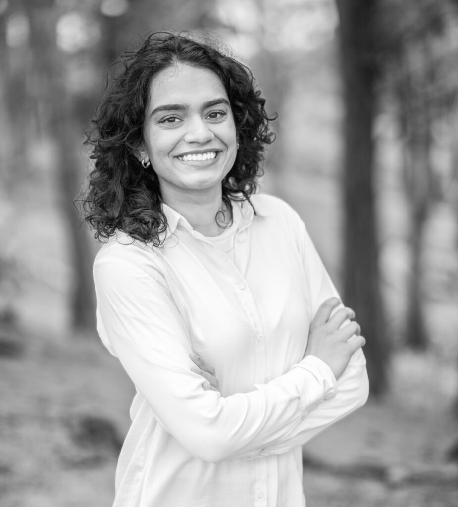 Black and white portrait of a woman with curly hair smiling outdoors.