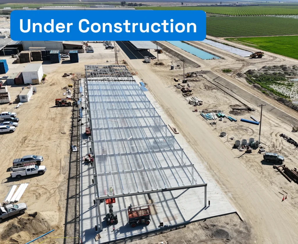 grimmway-premier-UC-v2-350x287 Aerial view of a solar canopy structure under construction at an industrial agricultural facility.