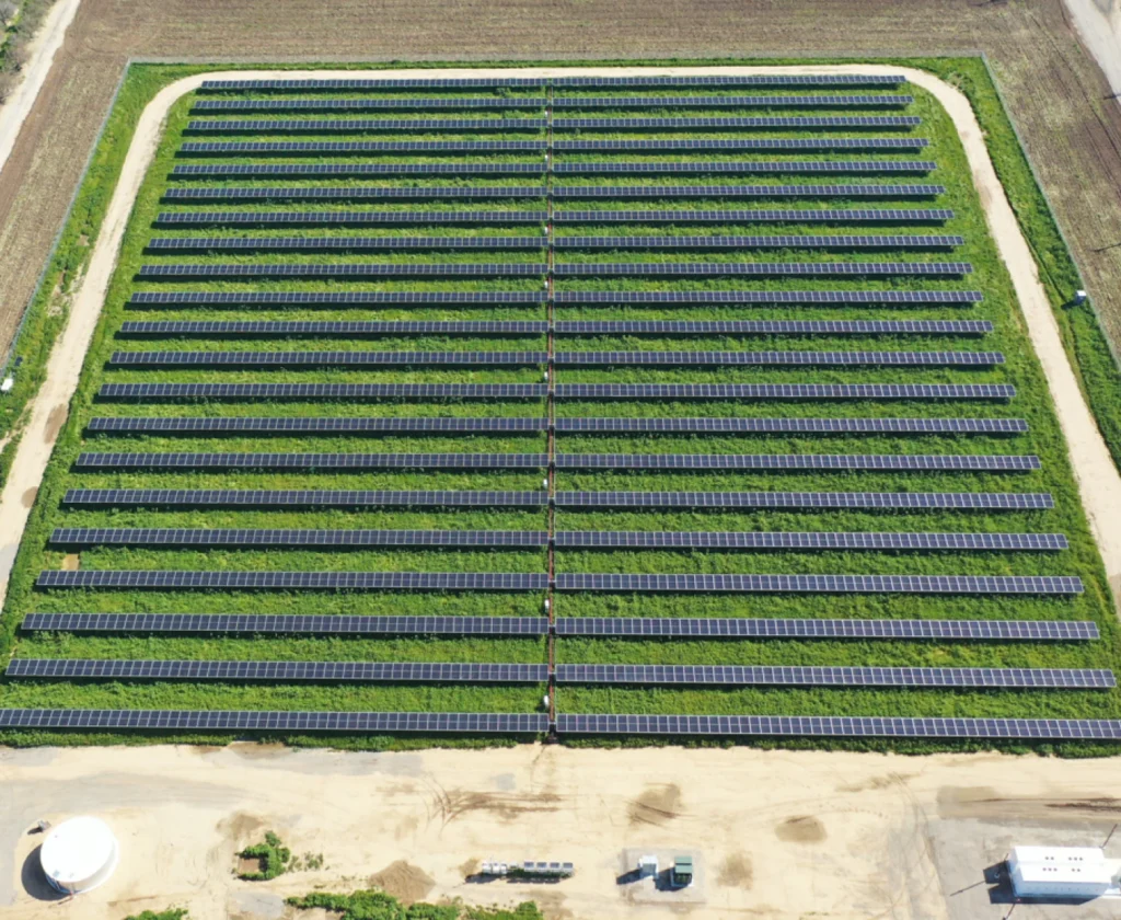 san-joaquin-700x574 Directly overhead aerial view of a symmetrical ground-mounted solar panel array on a grassy plot.